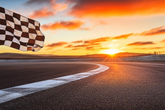 Checkered flag on a race track with a sunset in the background