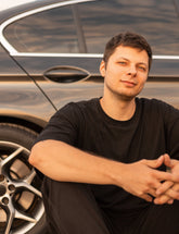 Man sitting in front of a black car with a blurred background