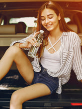 Woman sitting in the open trunk of a car holding a water bottle